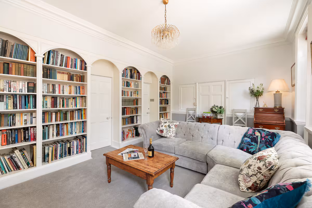 Abbie's Townhouse sitting room with grey chesterfield corner sofa and arched bookcases, central Bath