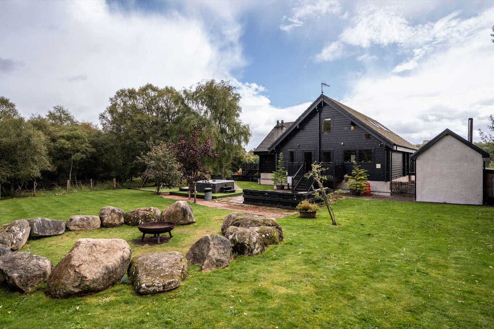 The lodge with a stone circle feature and lawn in the grounds
