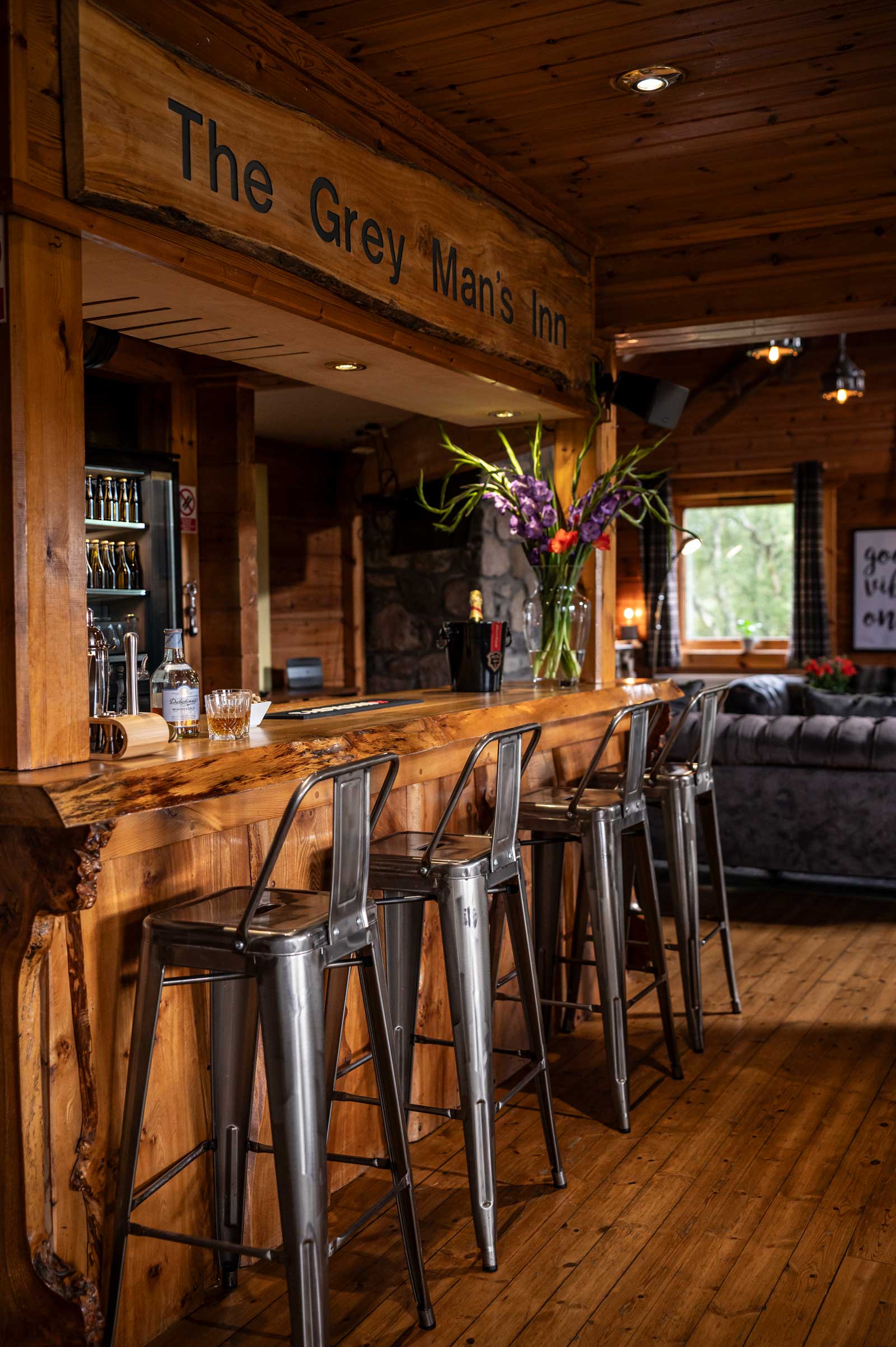 The Grey Man's Inn — a timber-clad bar inside the lodge with metal bar stools and a wooden counter