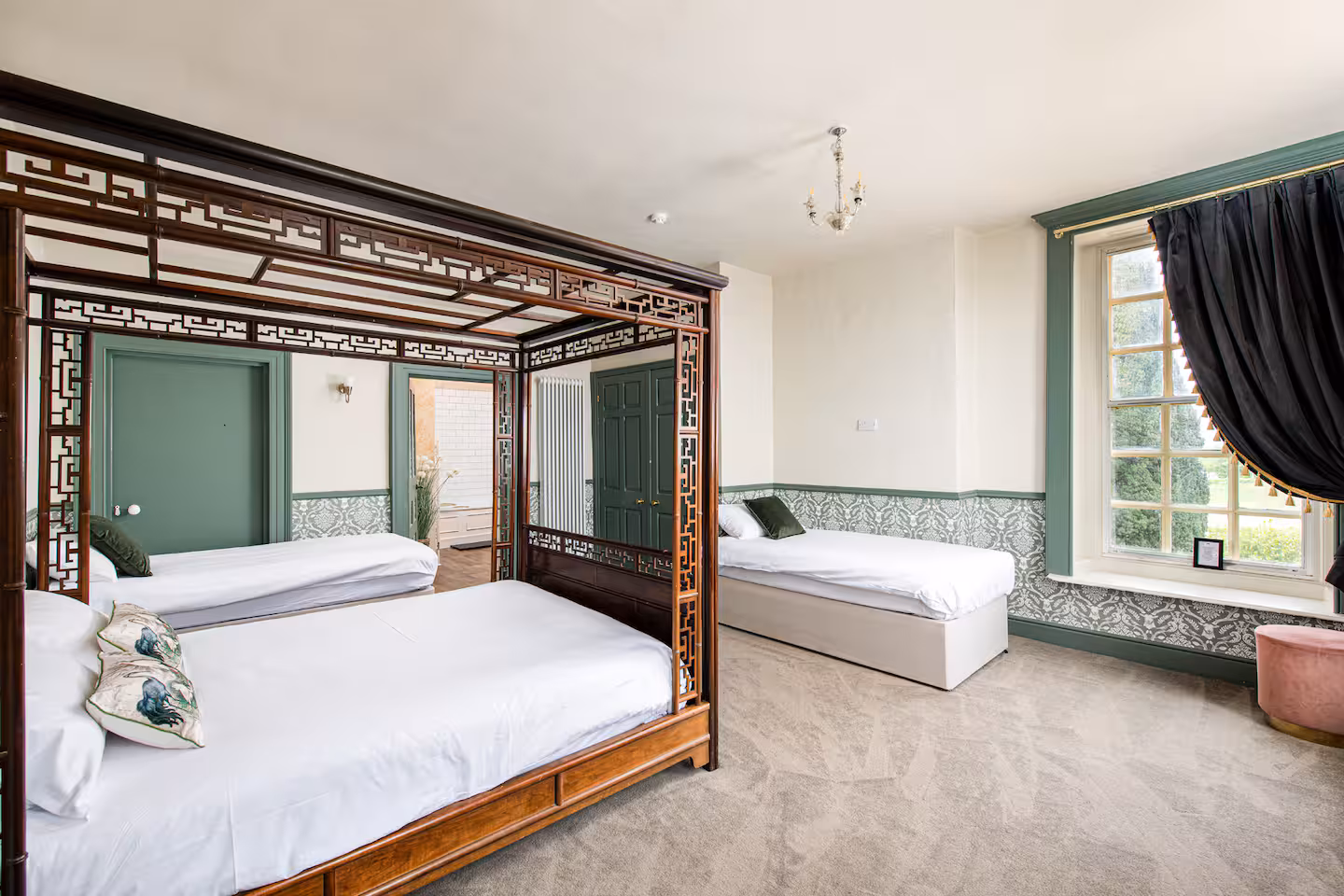 Master bedroom with carved four-poster bed, sage panelling and chaise under a sash window
