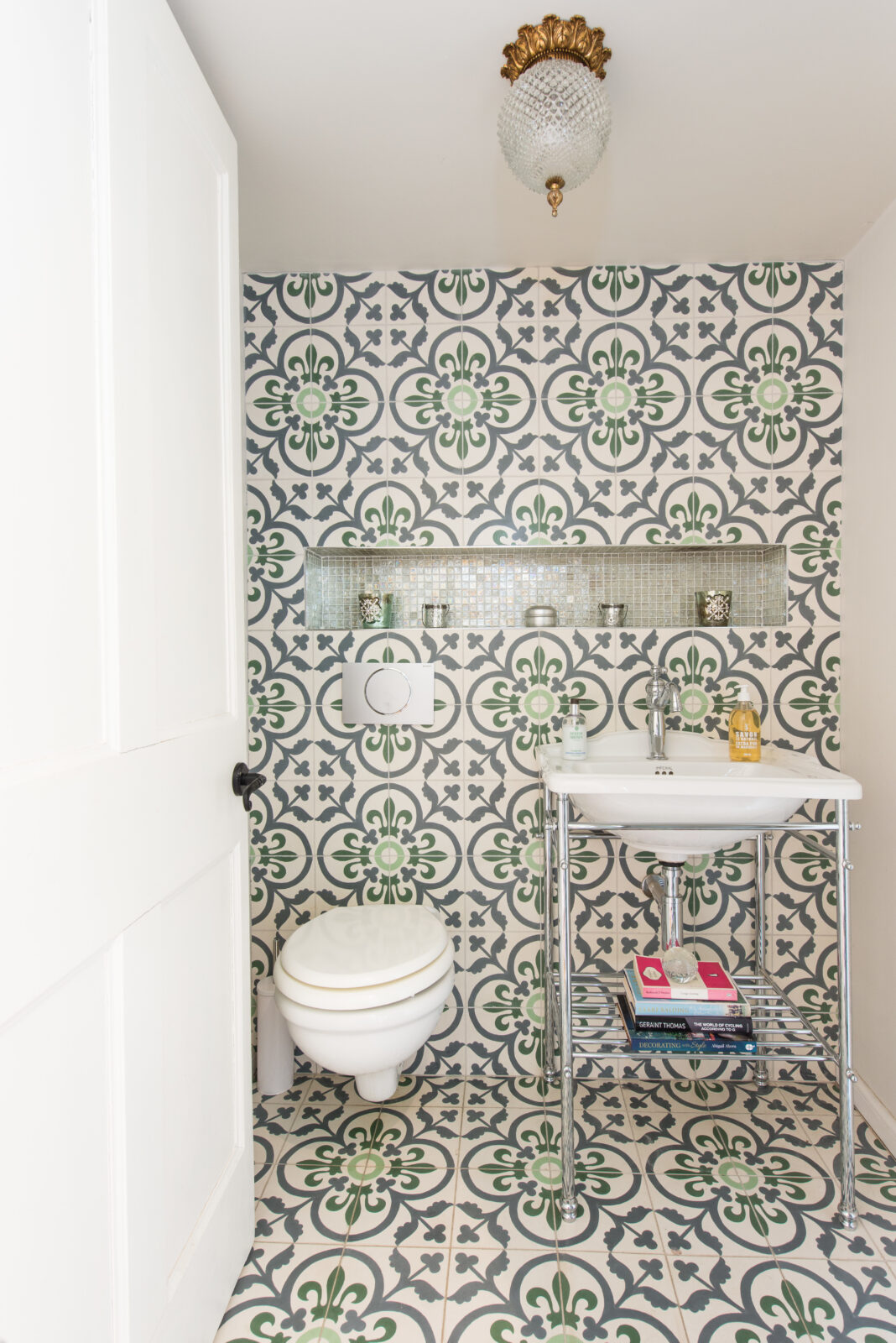 Cloakroom with green-and-cream encaustic floor and matching wall tiles, mosaic niche above sink