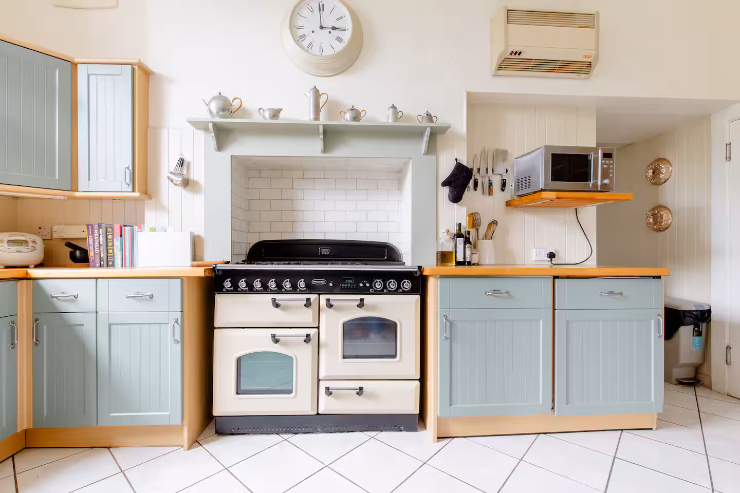 Country kitchen with pastel green cabinets, range cooker and white subway tile