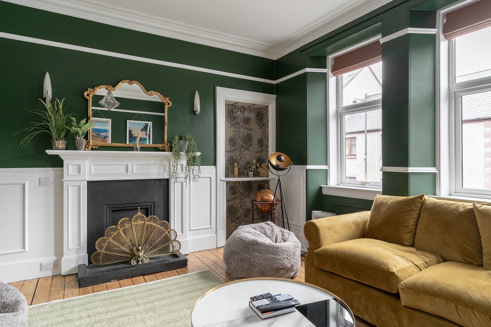 Highlands Townhouse lounge corner with mustard sofa, fluted brass floor lamp and peacock fan fireplace screen