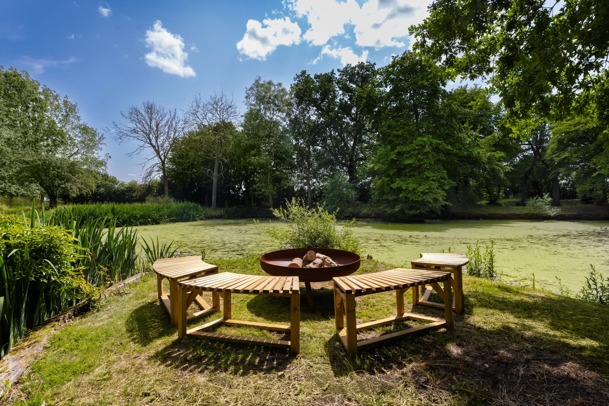 Lakeside firepit ringed with wooden benches beside the private lake, South East hen retreat