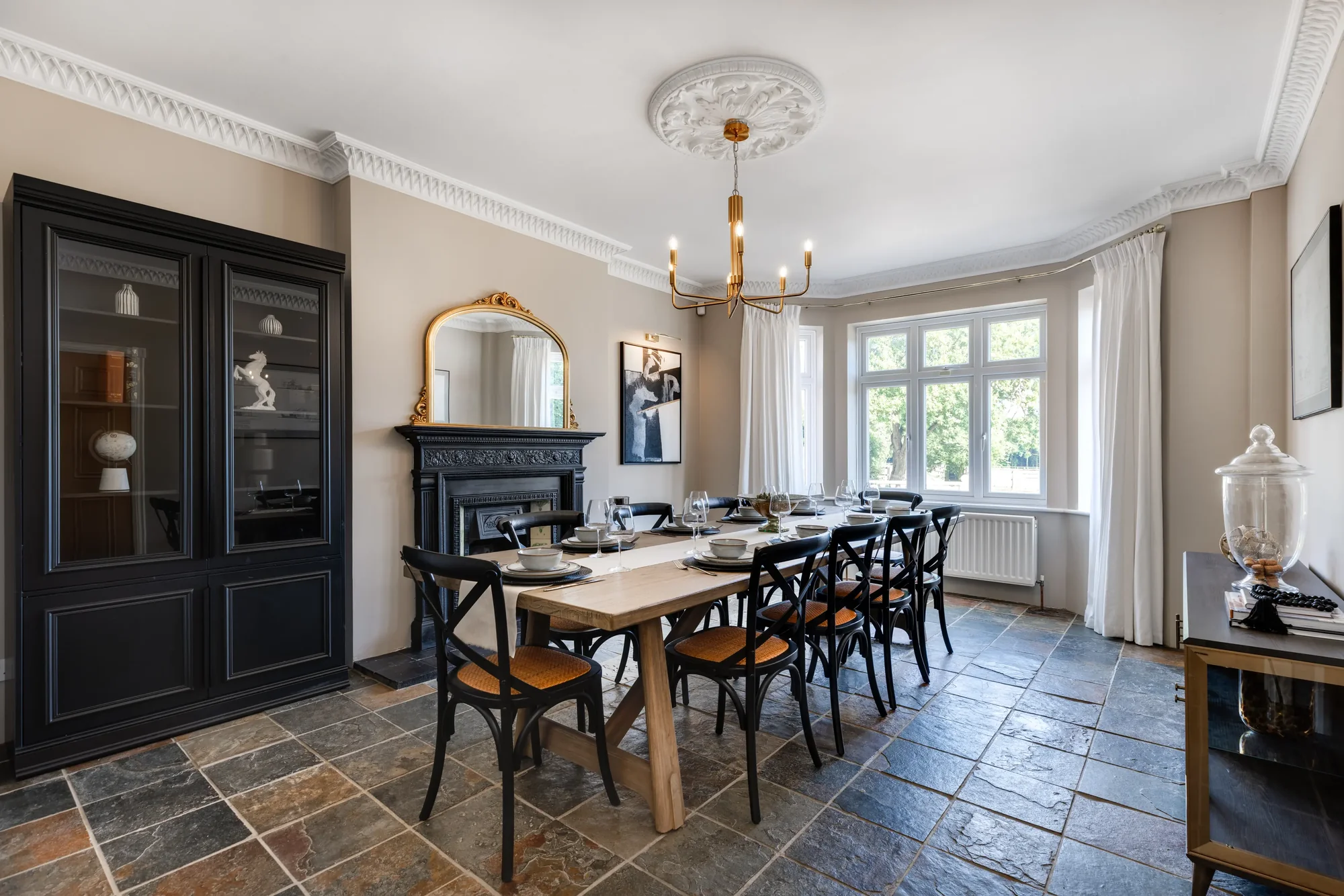 Formal dining room with long oak table, marble fireplace, gold mirror and slate floor, The Lakeside Retreat