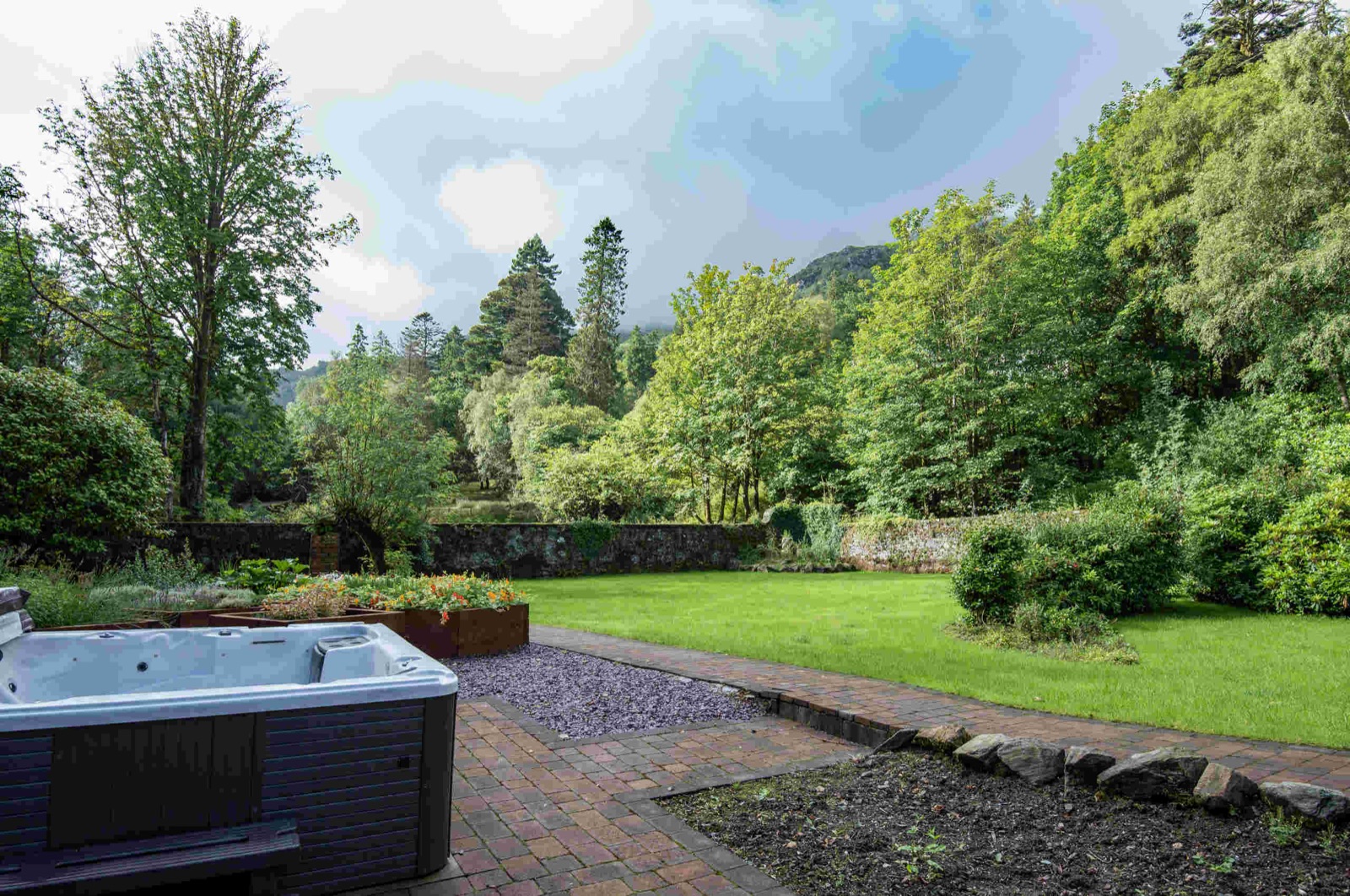 Outdoor hot tub on the patio looking over the walled garden lawn