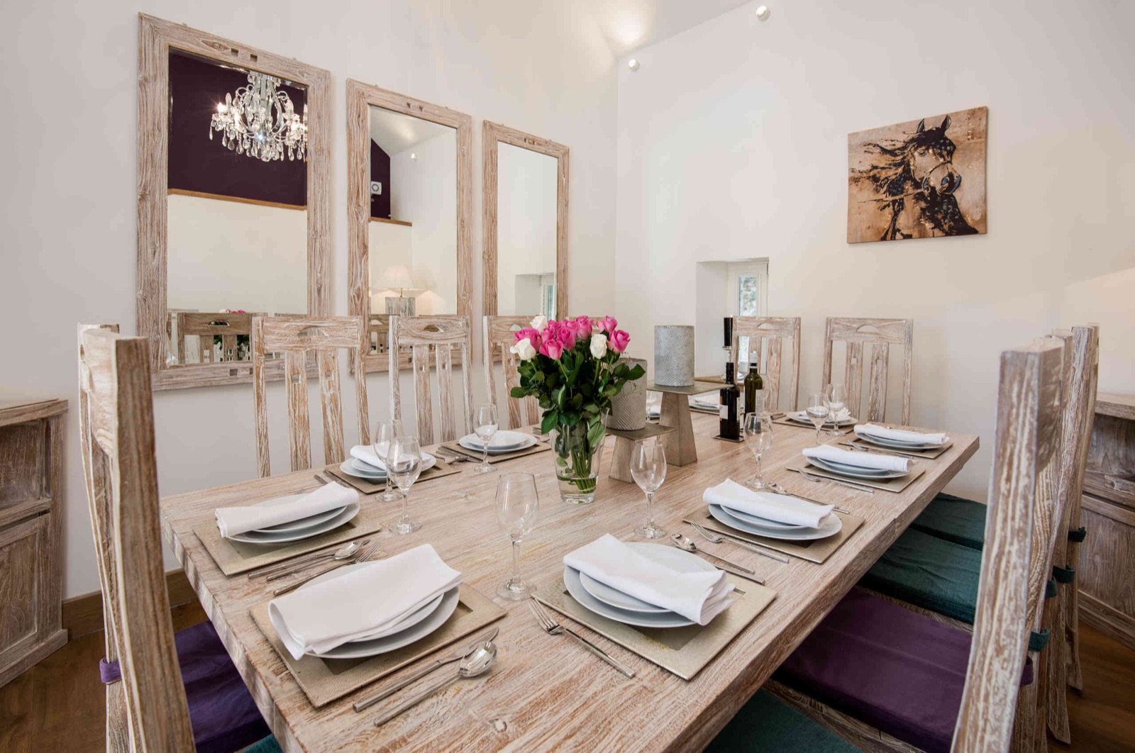 Long dining table laid for a dinner party with pink roses and mirrored wall