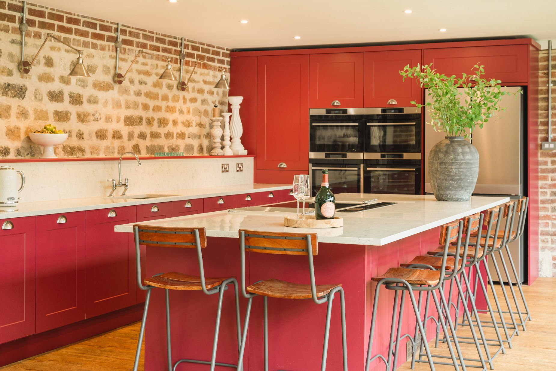Pinkertons pink shaker kitchen with exposed-brick wall, marble-topped island and wooden bar stools