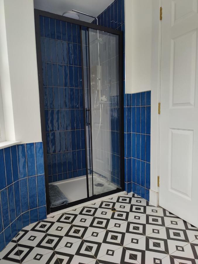 Bathroom with cobalt blue metro-tiled shower and a black-and-white diamond patterned floor