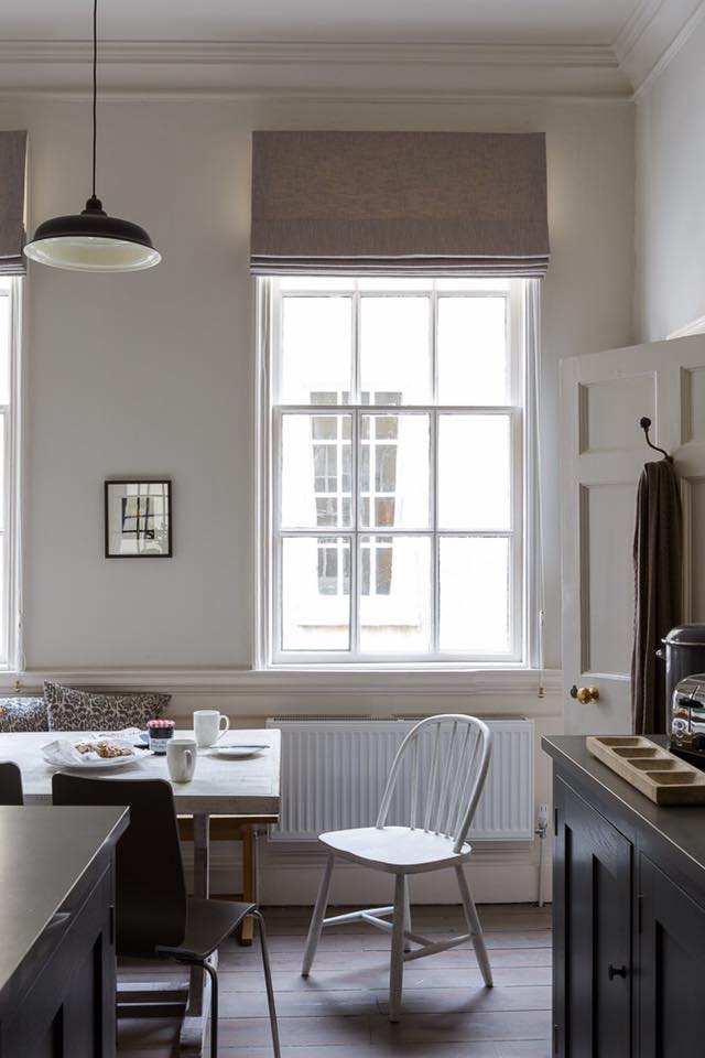 Kitchen breakfast nook with white dining table, dark cabinetry and a tall Georgian sash window