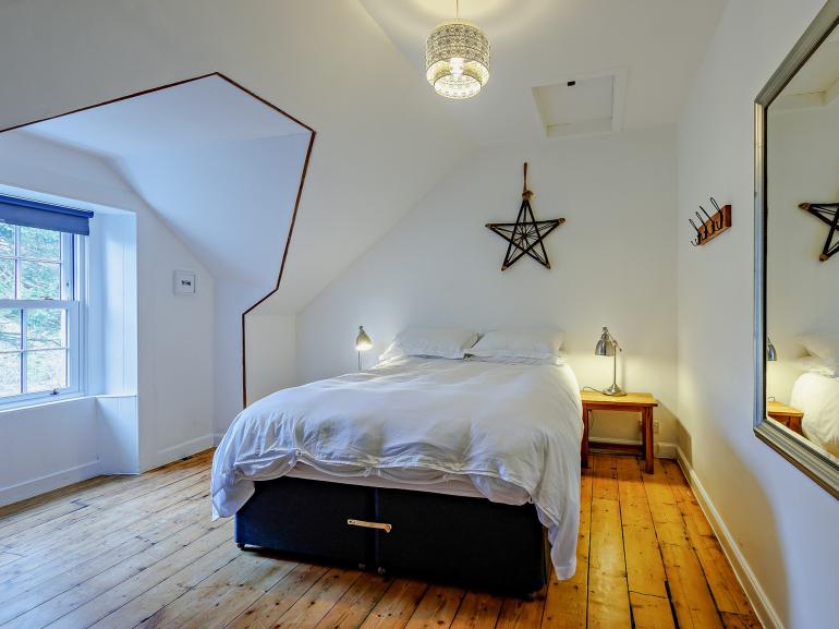 Attic double bedroom with sloped ceiling, pine floorboards and a star above the bed, The Scottish Lodge