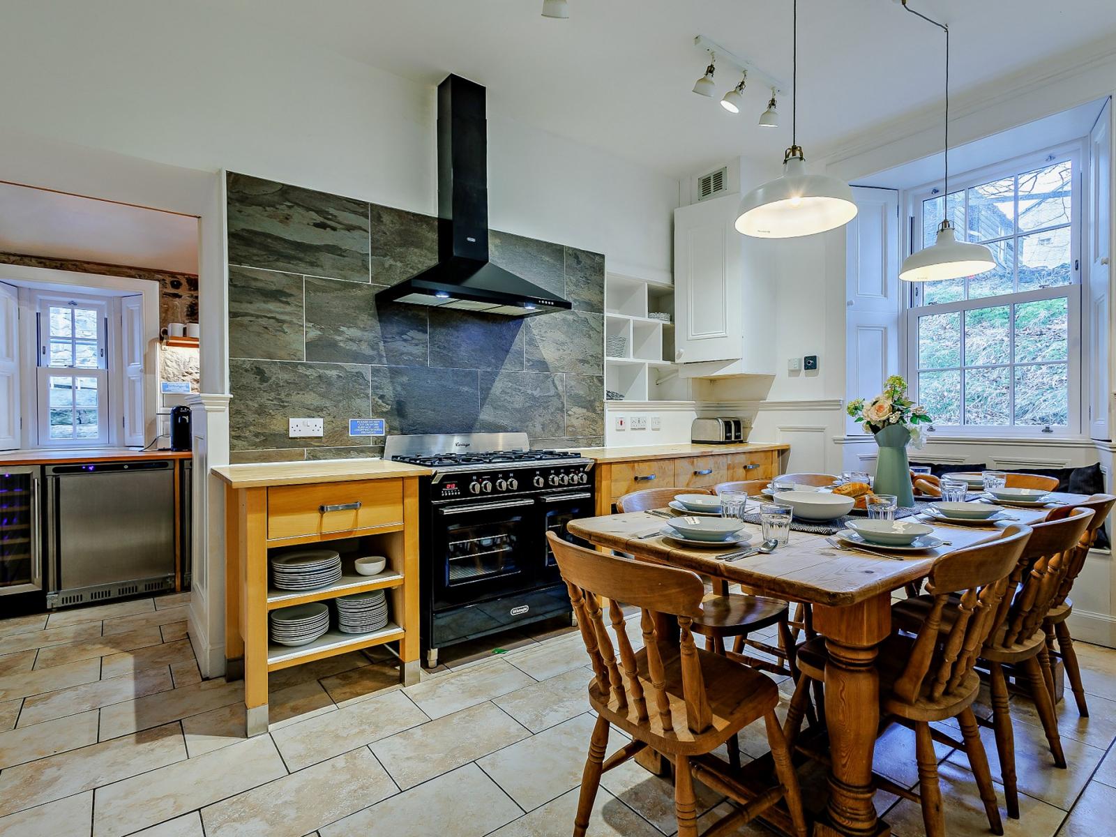 Country kitchen with range cooker, slate splashback and pine table set for breakfast, The Scottish Lodge