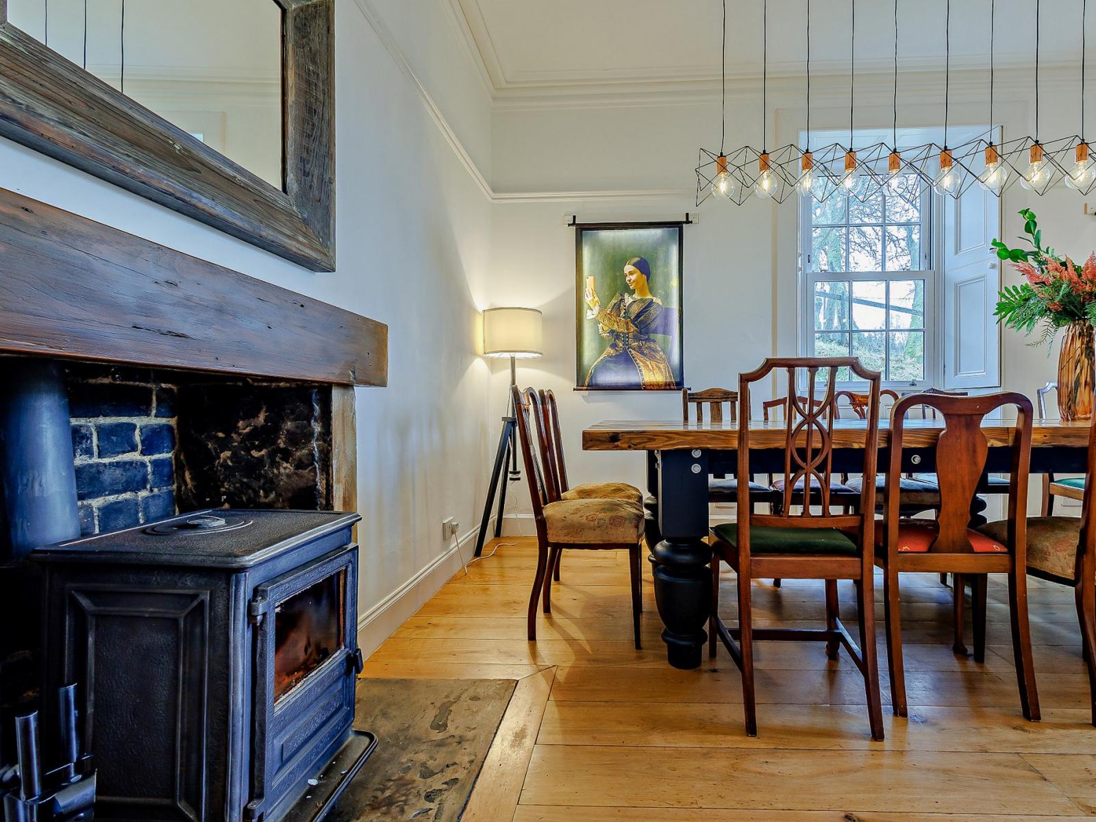 Dining room with cast-iron wood-burning stove, live-edge table and bare-bulb chandelier, The Scottish Lodge