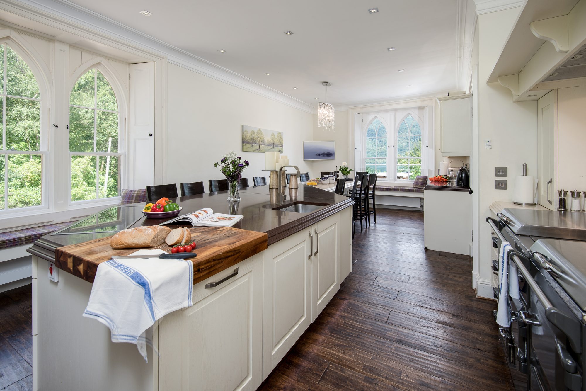 Long galley kitchen with central island, gothic arched windows and dark wood floor, Sequoia House
