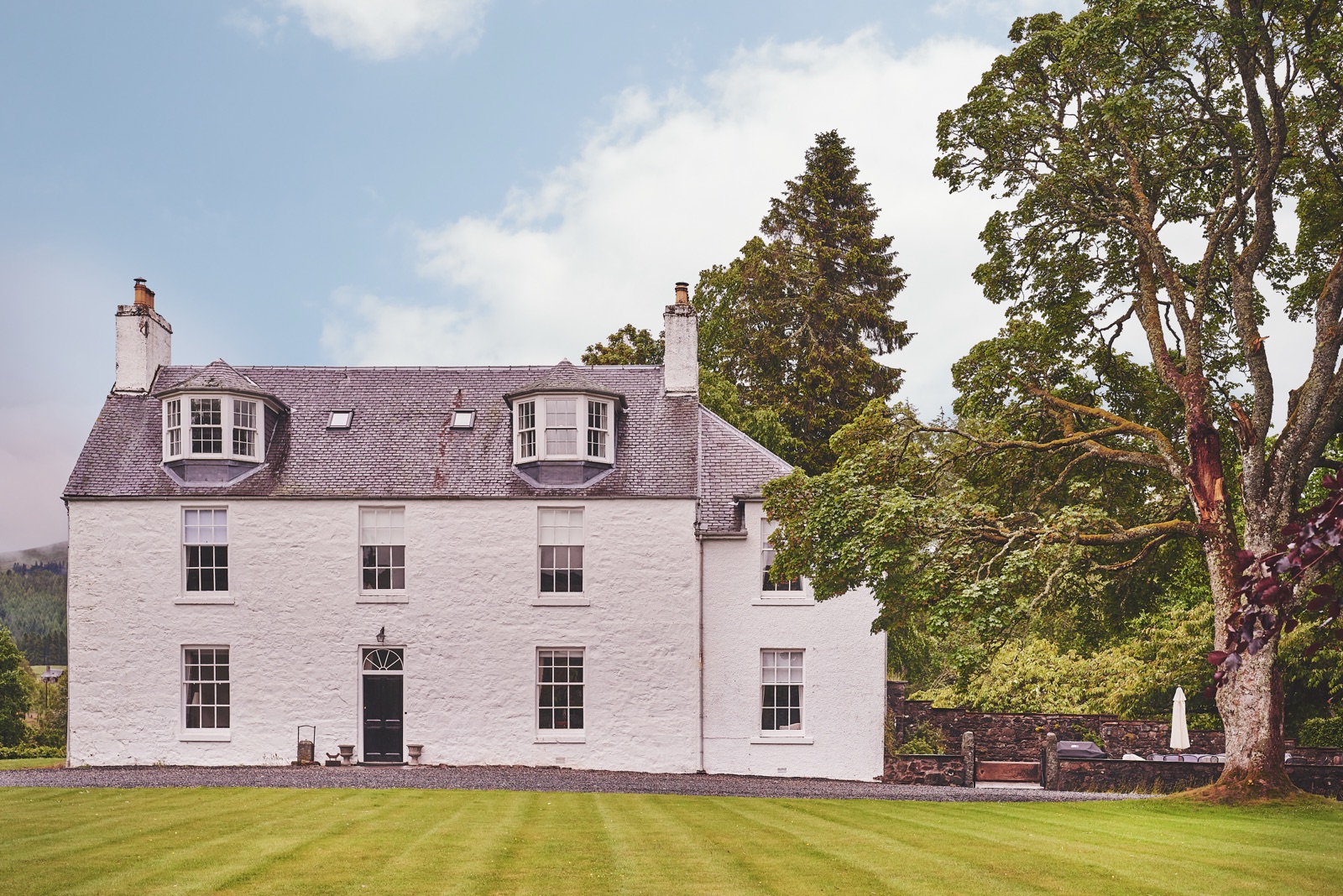 The white Georgian façade of The Loch House across a striped lawn, Highland Perthshire