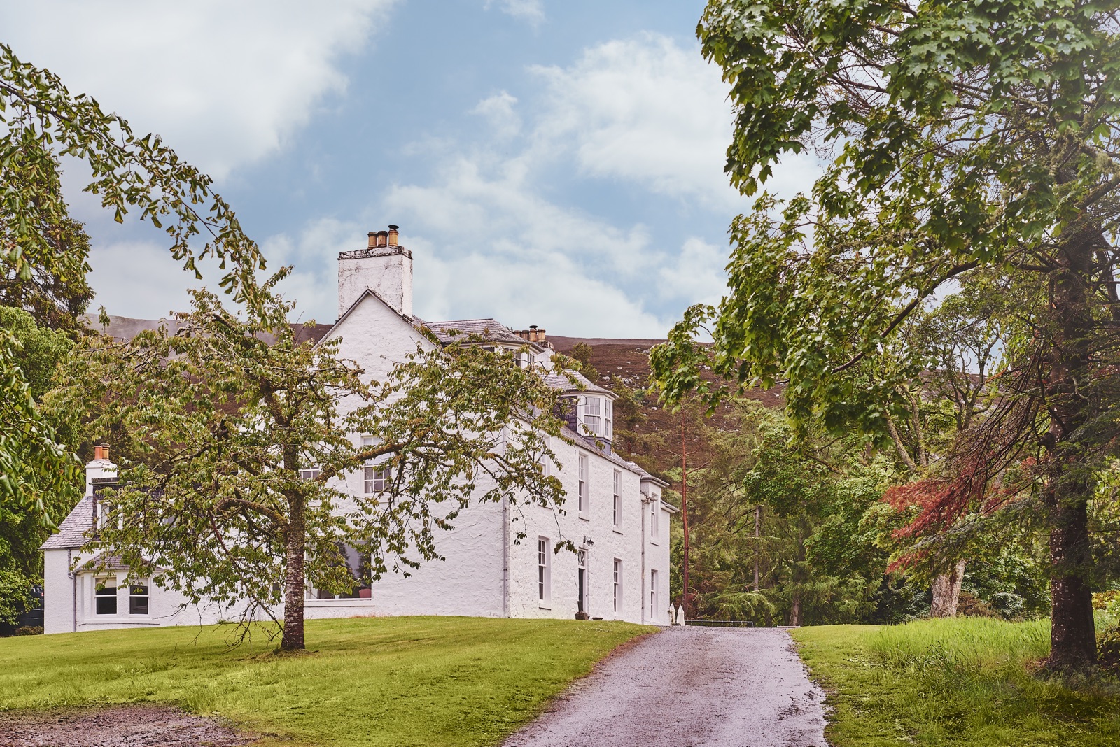 The white lodge glimpsed through the trees from the lawn