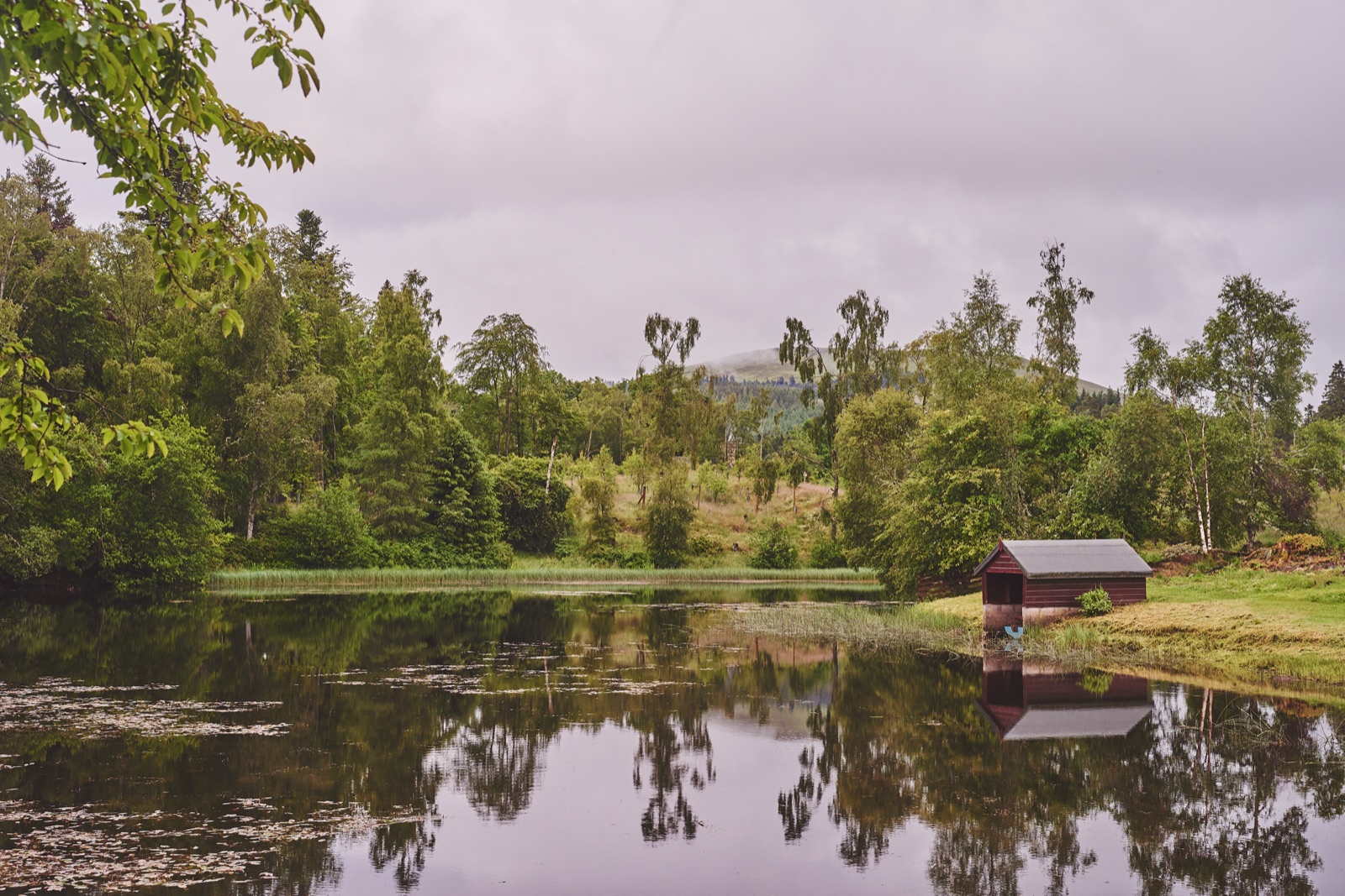 The private loch with a little red boathouse on the bank and Highland hills behind