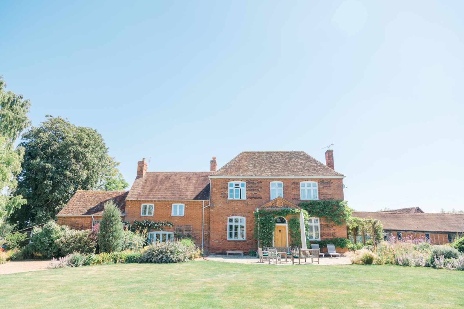The Old Farmhouse hen party house, red-brick 18th-century farmhouse behind a wide lawn in Bedfordshire