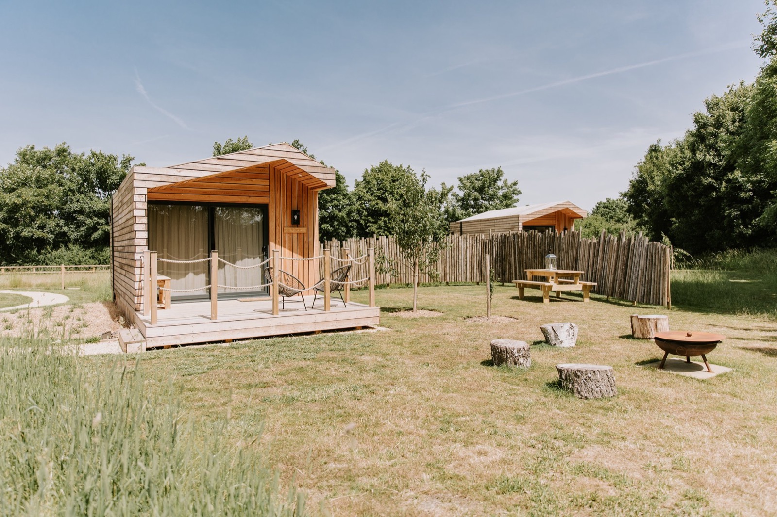 The Wildflower Cabins hen party glamping site, timber cabins with decking and a fire pit in a Bedfordshire meadow