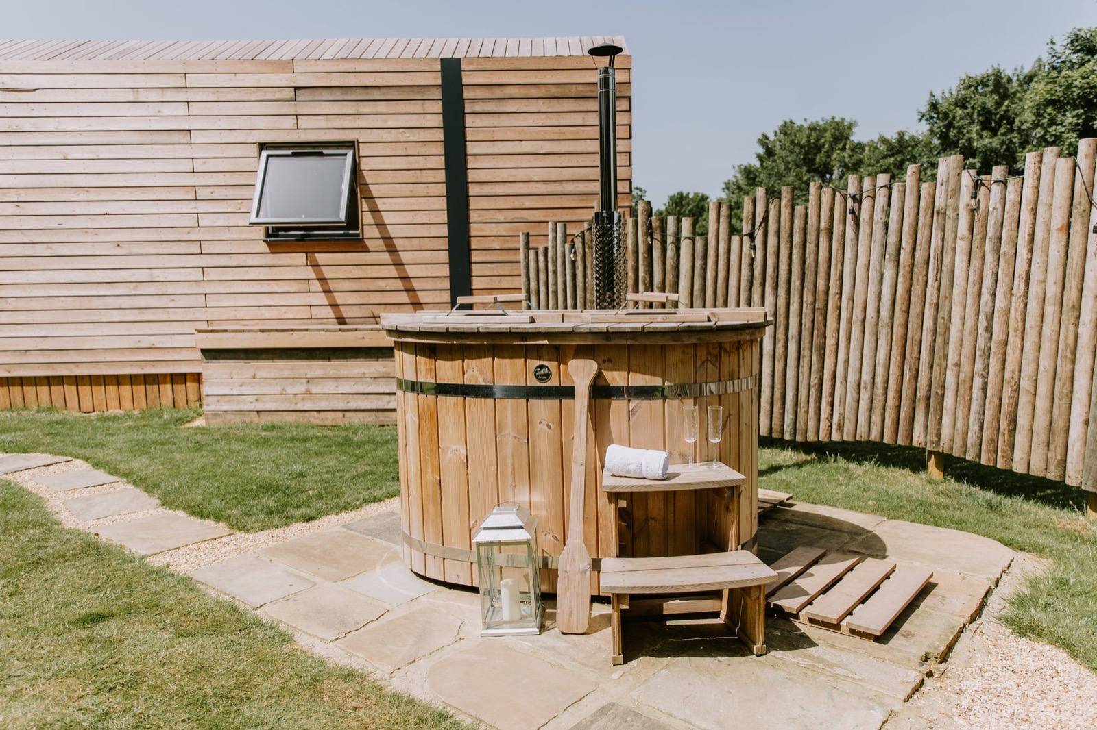 Wood-fired cedar hot tub with steps and a lantern on the patio beside a cabin, The Wildflower Cabins