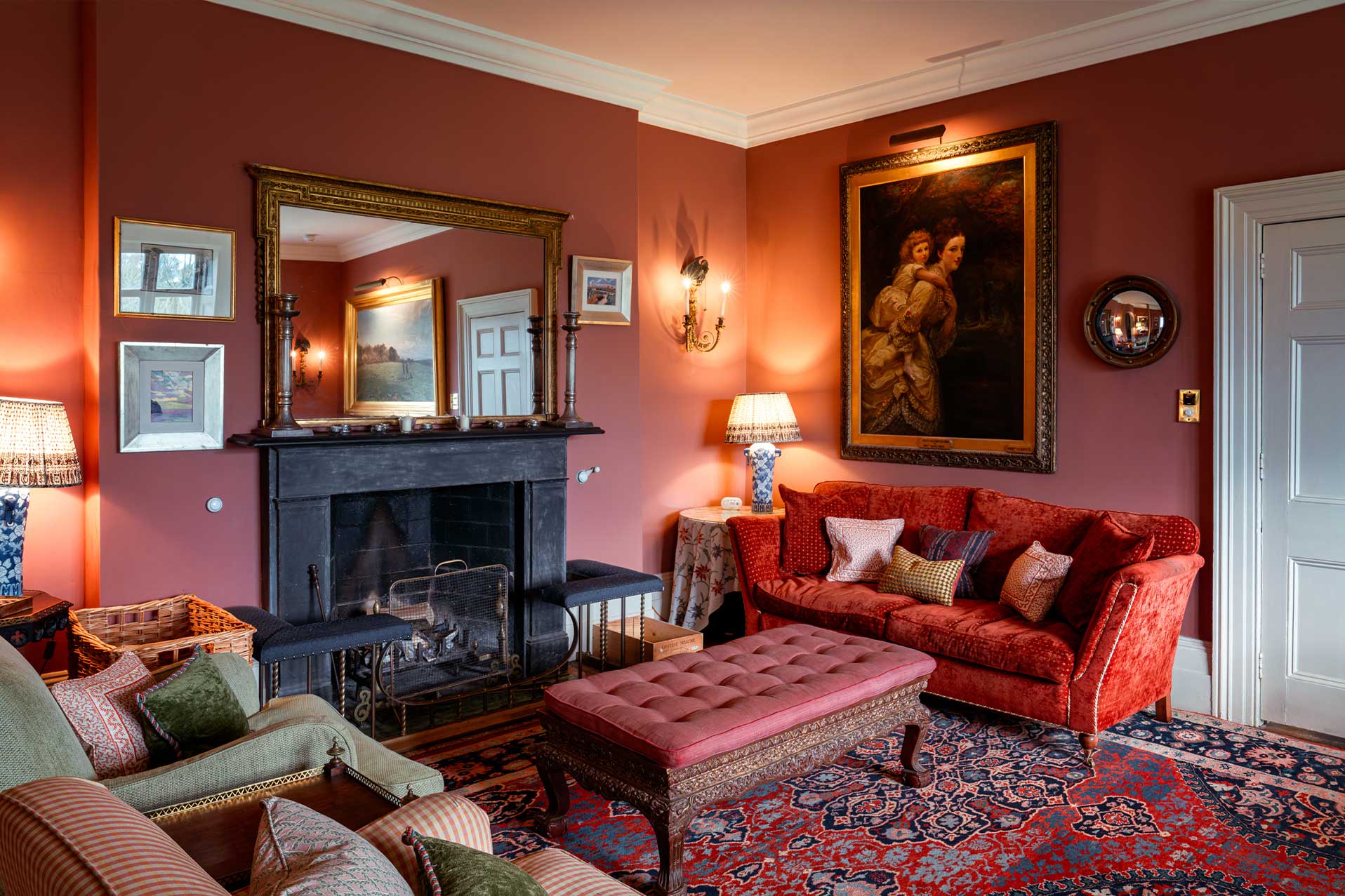 Deep red drawing room with crackling open fire, red velvet sofa and an oil portrait, The Country Social