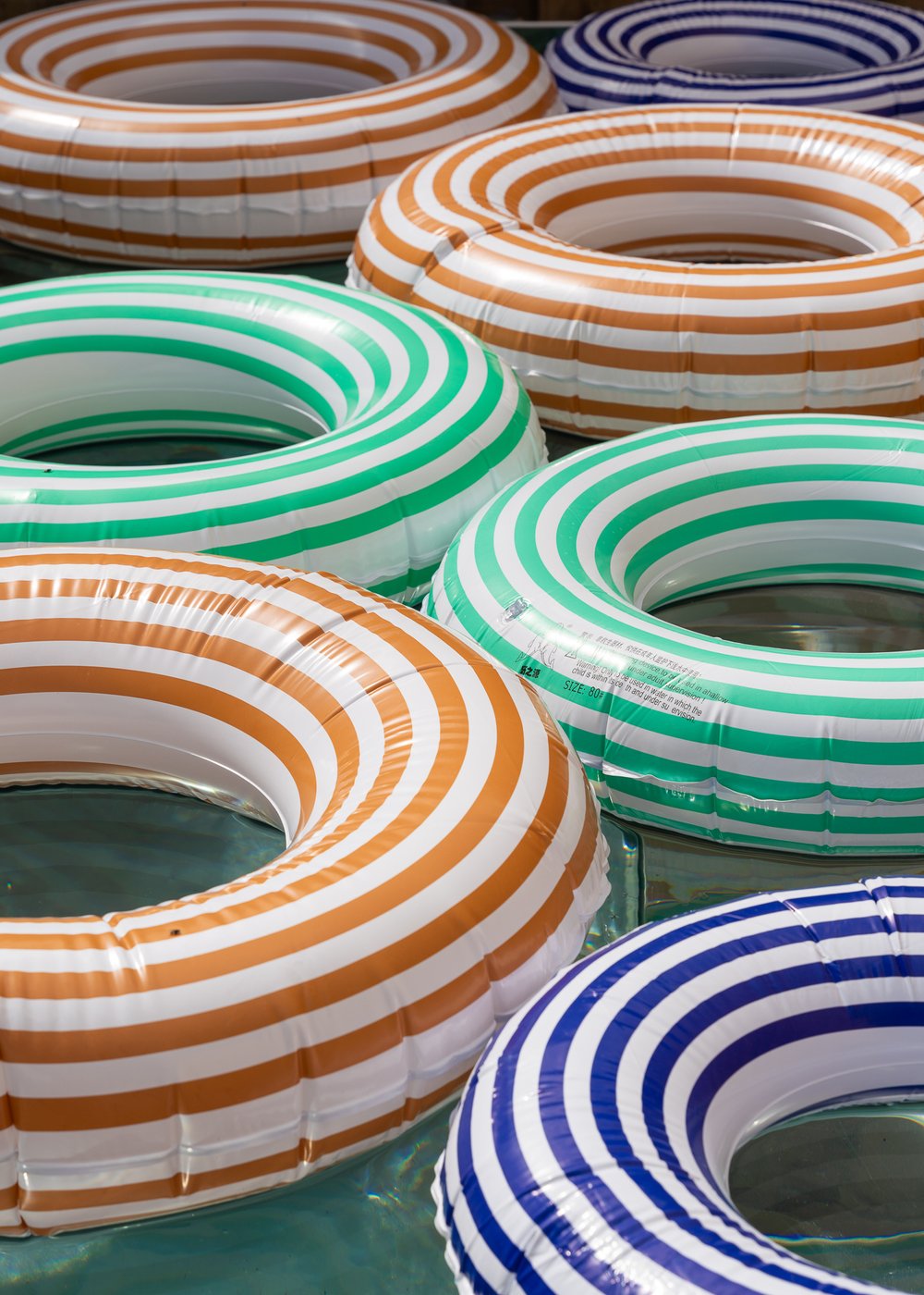 Orange, green and blue striped ring floats drifting on the water