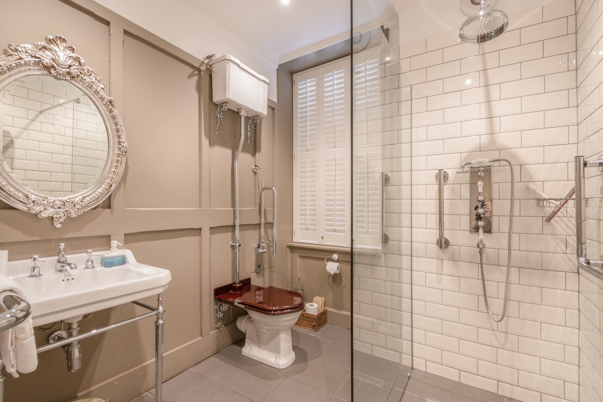 Bathroom with cream panelling, white metro tiles, throne loo with high-level cistern and ornate silver mirror