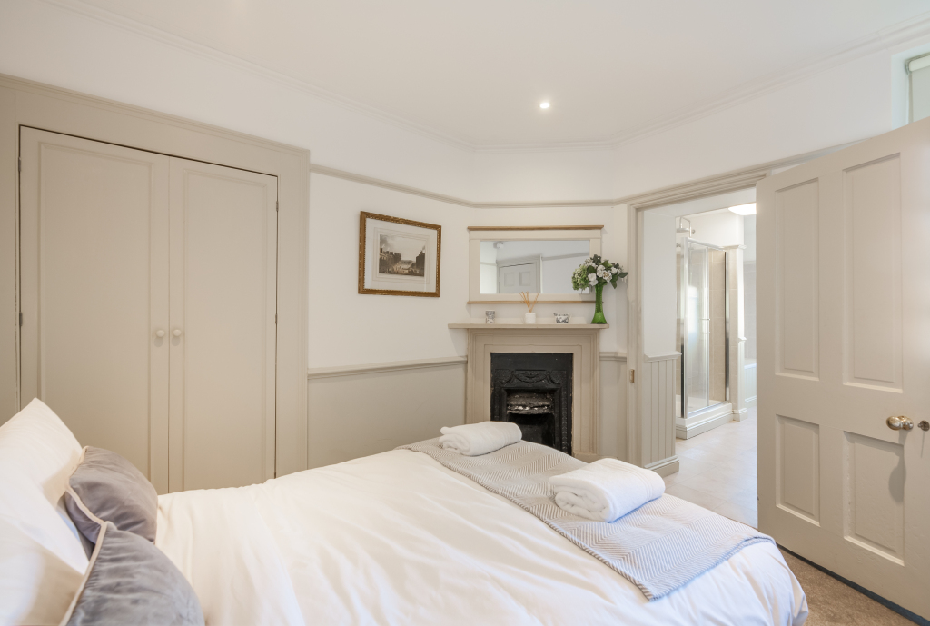 Cream double bedroom with cast-iron fireplace, gilt mirror and doorway through to the ensuite, Tillie's Townhouse