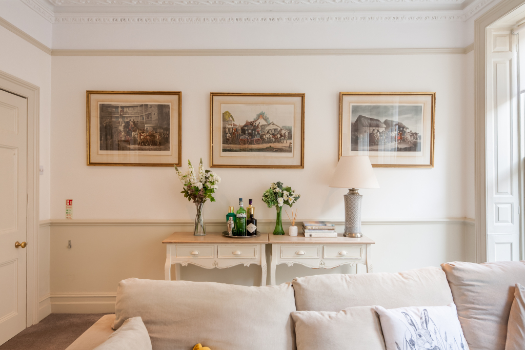 Tillie's Townhouse sitting room with cream sofa, three framed vintage carriage prints and ornate cornicing