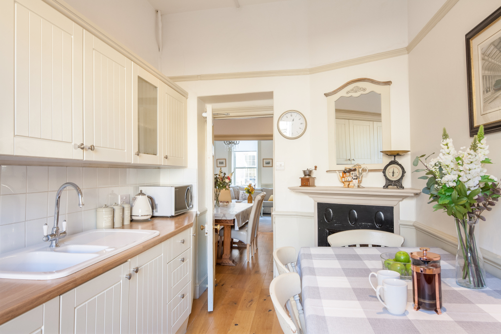 Cream galley kitchen with breakfast nook, gingham tablecloth and view through to the dining room beyond, Tillie's Townhouse