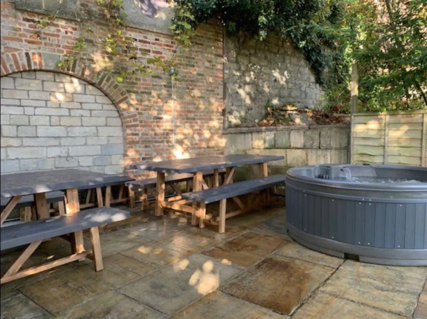 Walled courtyard with two long benches and outdoor hot tub at Victorian Townhouse Bath