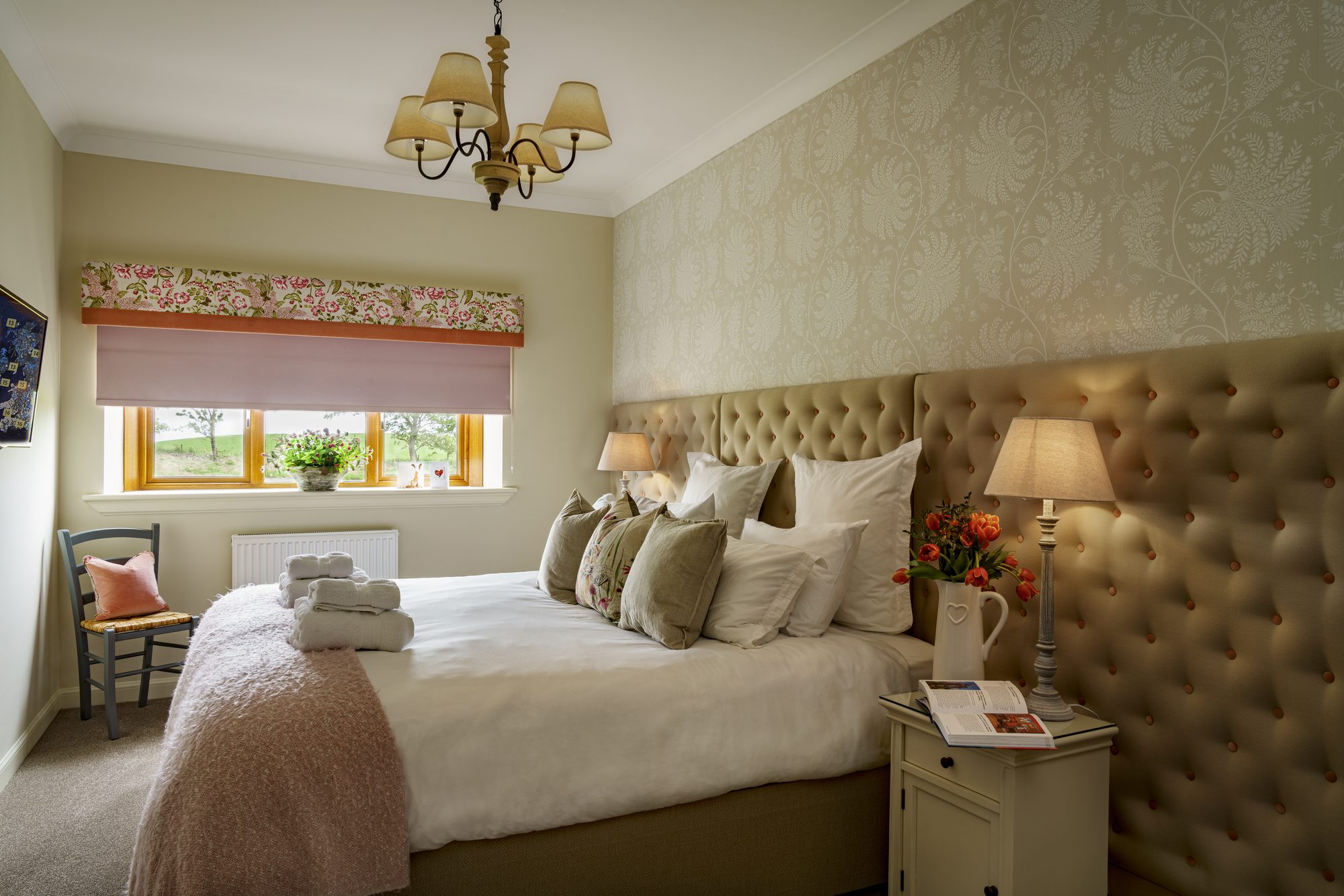 Bedroom with tufted velvet headboard, floral pelmet and country view window seat at Writers Bow House