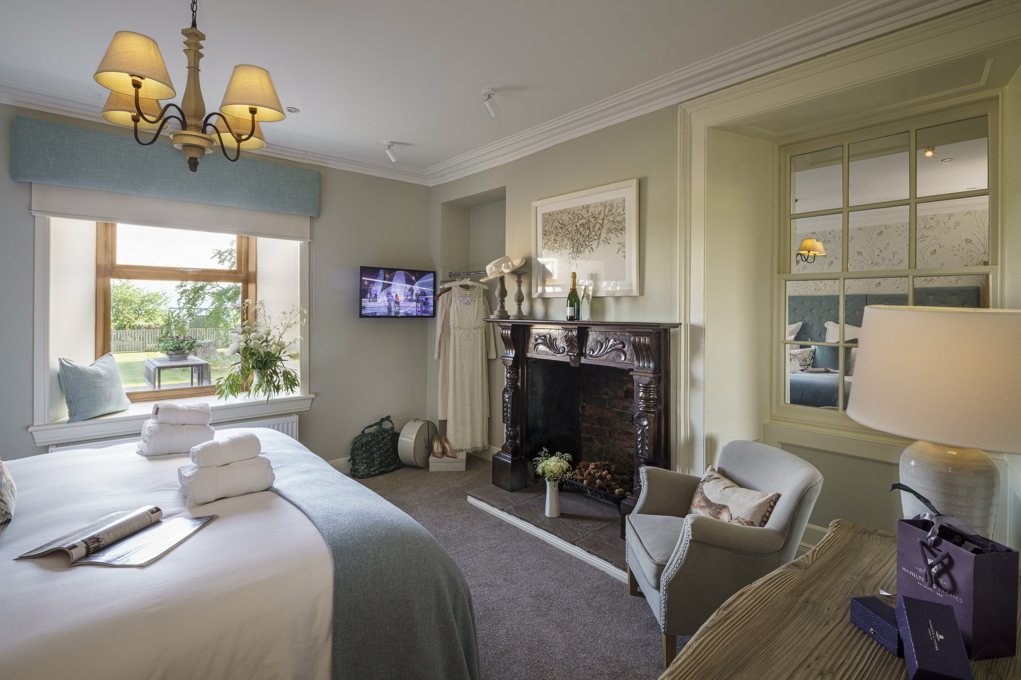 Bedroom with original carved fireplace, mirror alcove and the bride's dress hanging at Writers Bow House