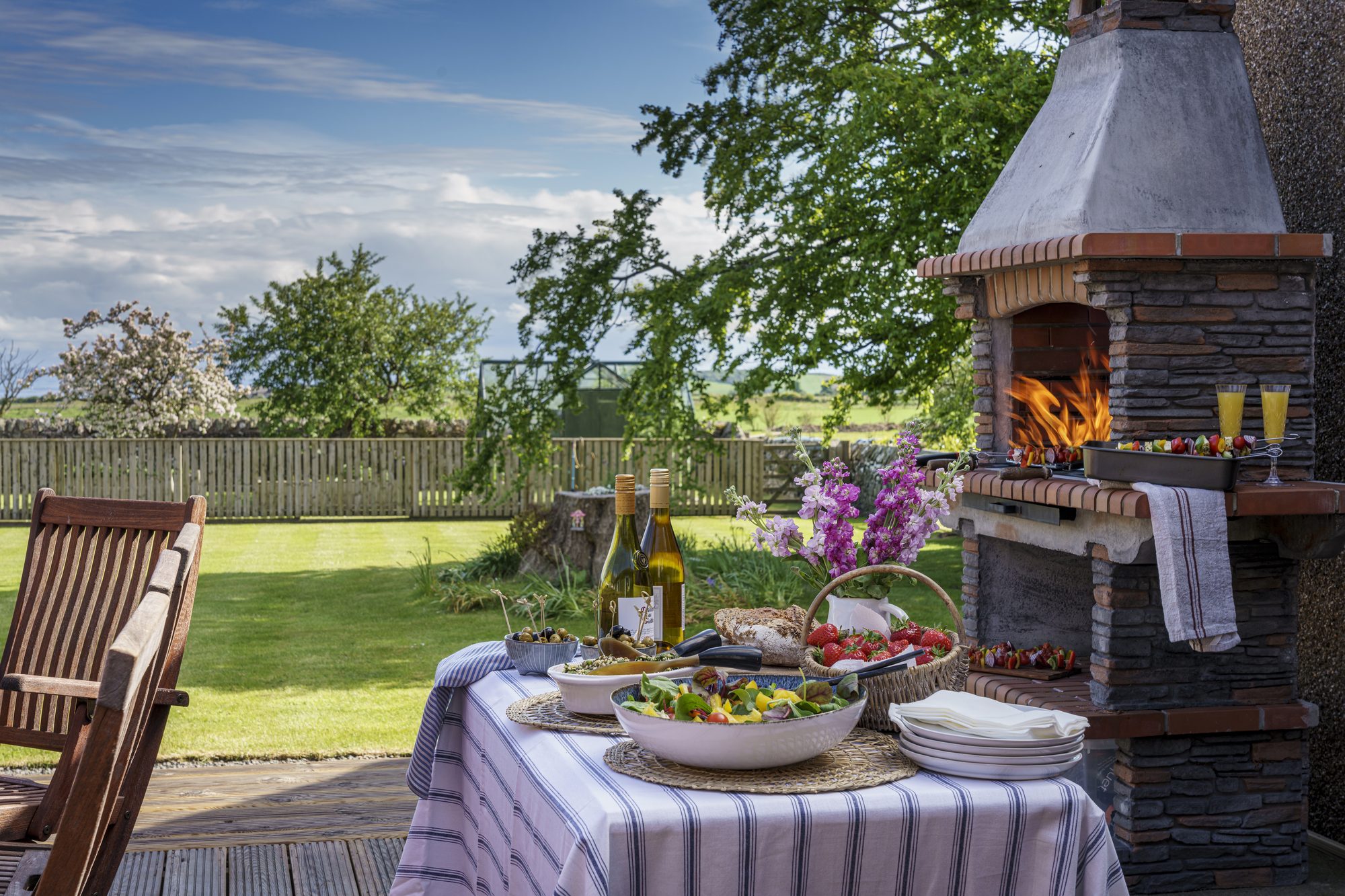 Writers Bow House garden patio with outdoor dining table, Mediterranean-style BBQ and wildflower planting