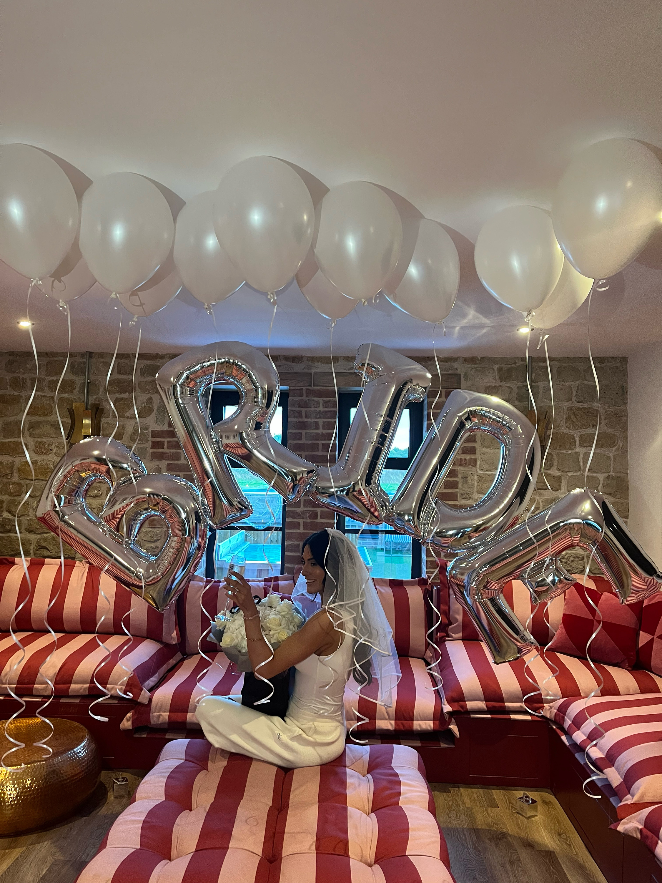 Bride under a 'BRIDE' silver balloon arch, Bath hen party