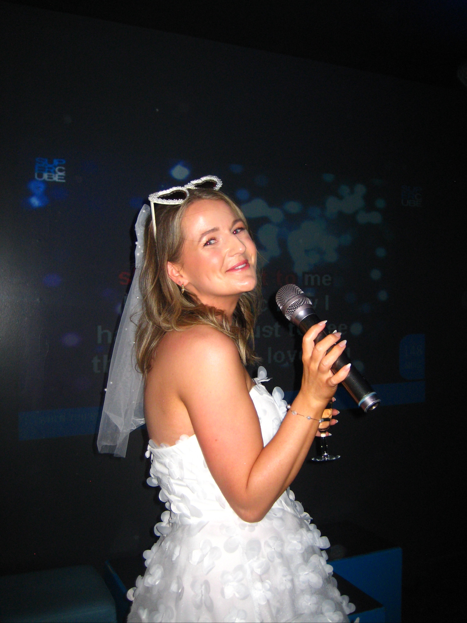 Hen group singing in a private karaoke pod, microphones up