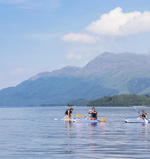 Hen group paddle boarding on Loch Lomond at sunset, Scottish Highlands